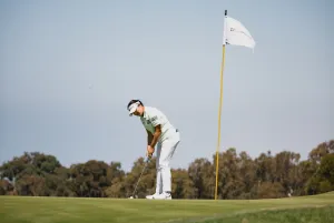 golfer next to hole with flag