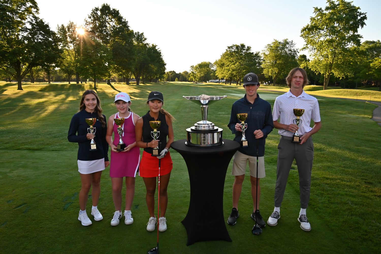 Golfers surrounding trophy